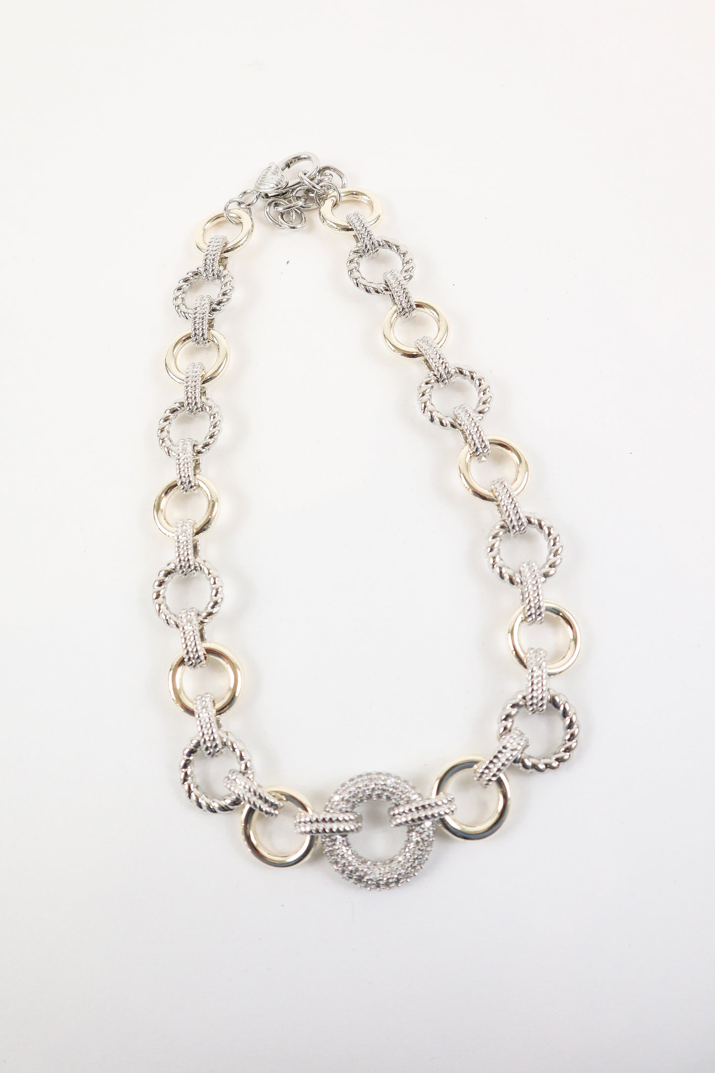 Two-tone gold and silver link statement necklace with textured circular pendant, women’s boutique mixed metal fashion jewelry.