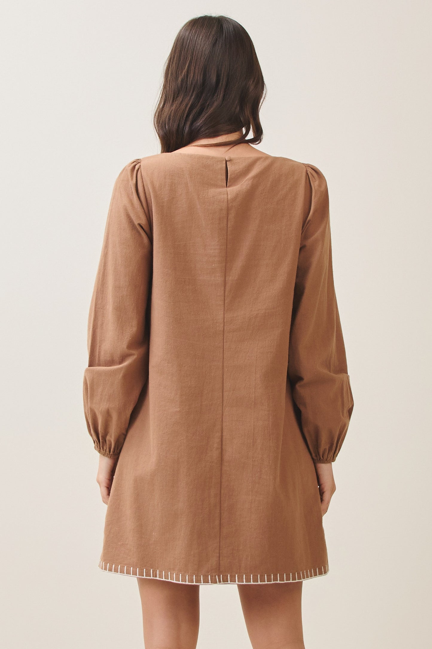 100% cotton embroidered mini dress featuring long volume sleeves, decorative whipstitch detailing, and a relaxed feminine silhouette.