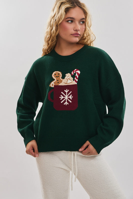 Spread cozy holiday cheer in this playful sweater featuring a festive cocoa mug motif.
