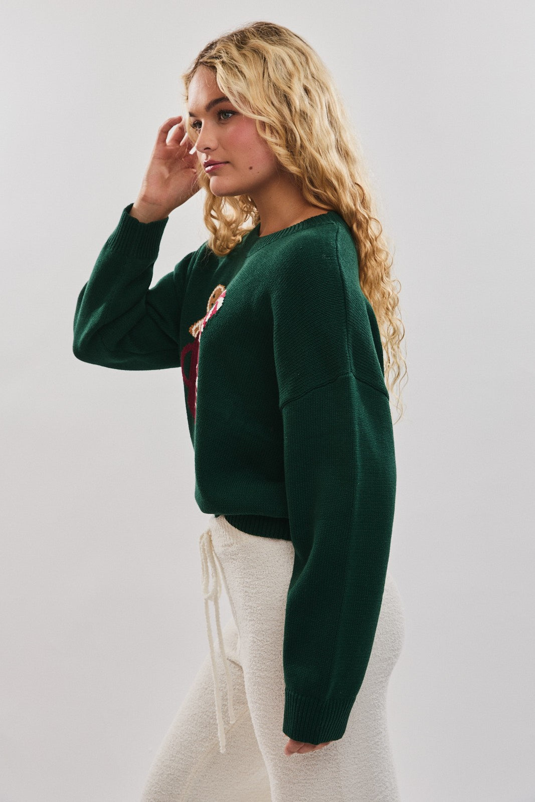 Spread cozy holiday cheer in this playful sweater featuring a festive cocoa mug motif.
