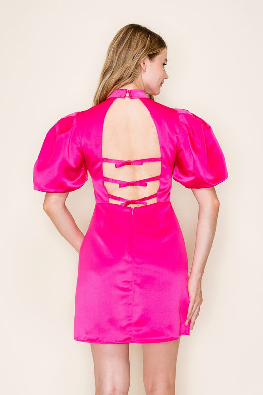 A bold magenta mini dress with puff sleeves, open back, and triple bow accents.