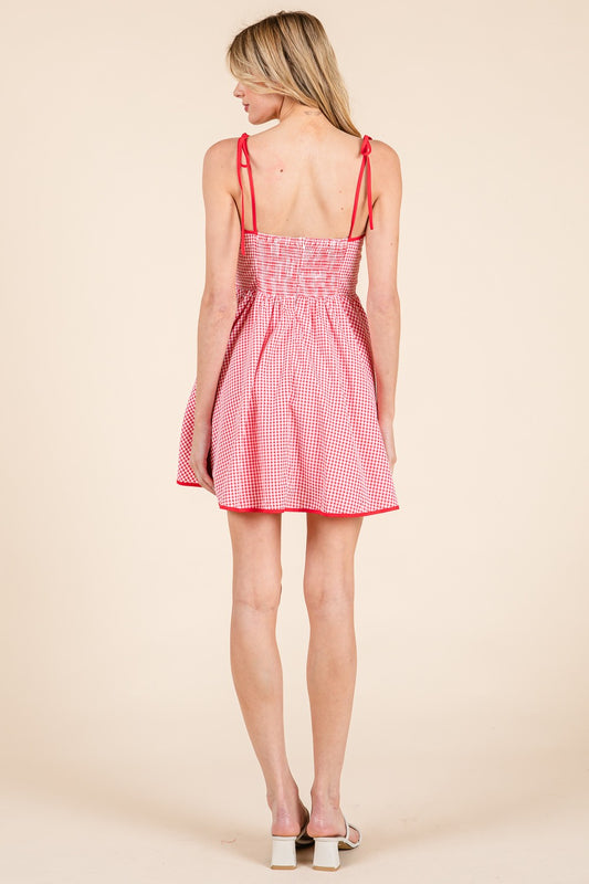 A charming gingham mini dress with ribbon detail and a flattering fit.
