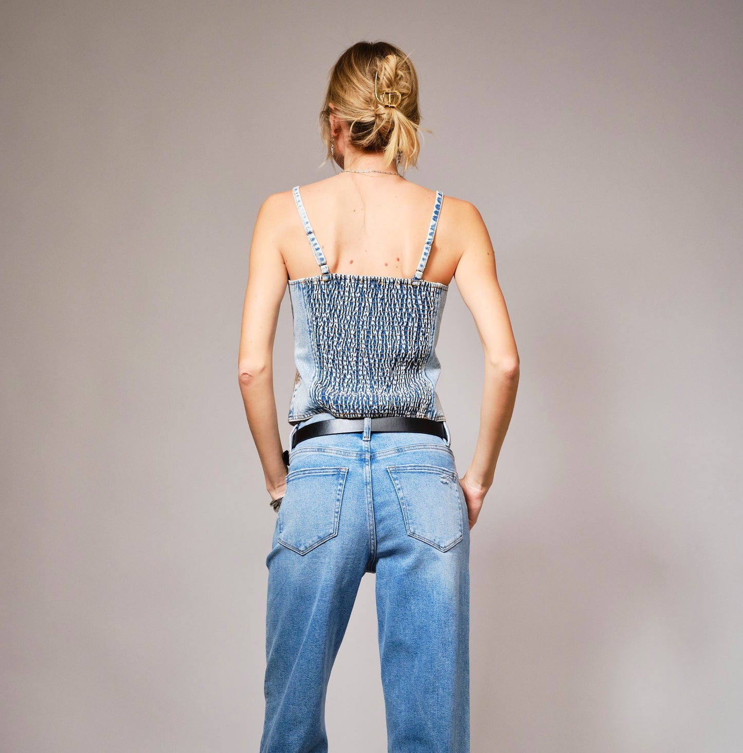 A denim corset top with sparkling sequin bow embroidery and a flattering structured fit.