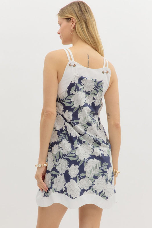 A feminine floral print mini dress with delicate shoulder straps and a wave-patterned hem for a touch of charm.