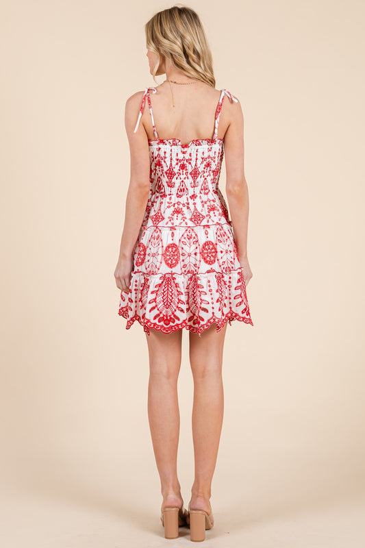 A flirty smocked mini dress with delicate embroidery and ruffle details.