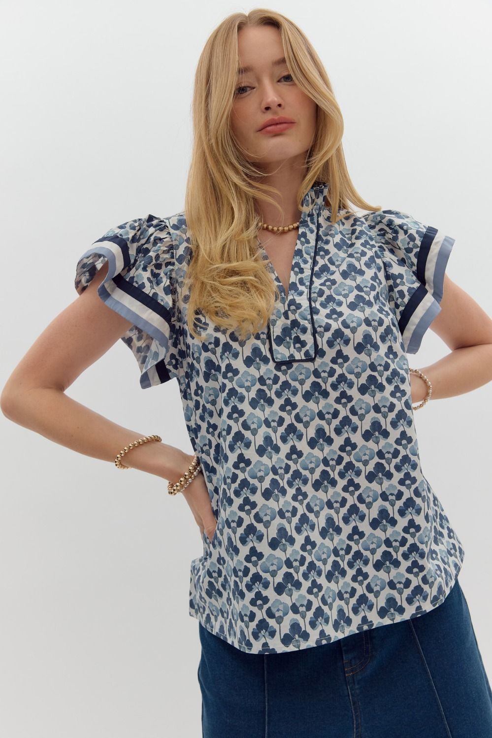 A floral print pullover top with ruffle split V-neck and flutter sleeves with a multicolor hem.