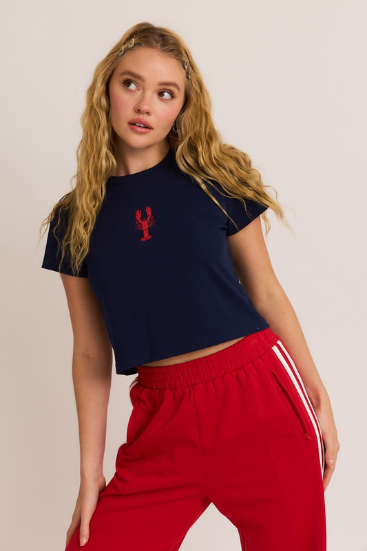 A fun and flirty baby tee featuring a bold lobster graphic and a classic round neckline—perfect for sunny days and casual vibes.