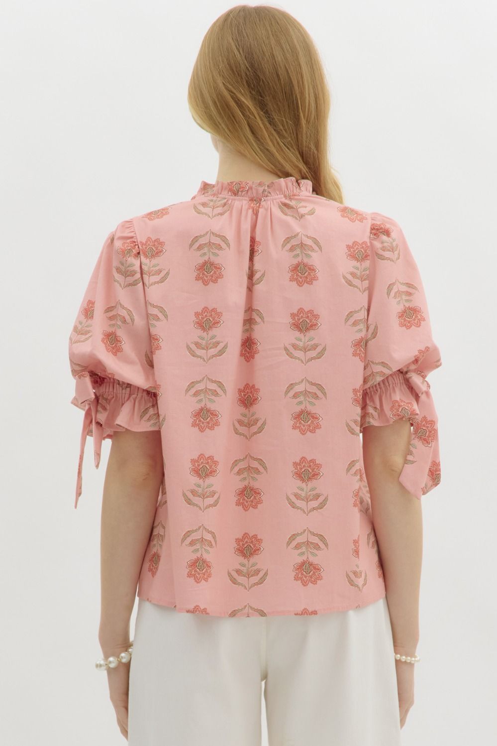 A romantic floral pullover top with a ruffled split neckline, bow accent, and bubble sleeves—feminine charm in an easygoing silhouette