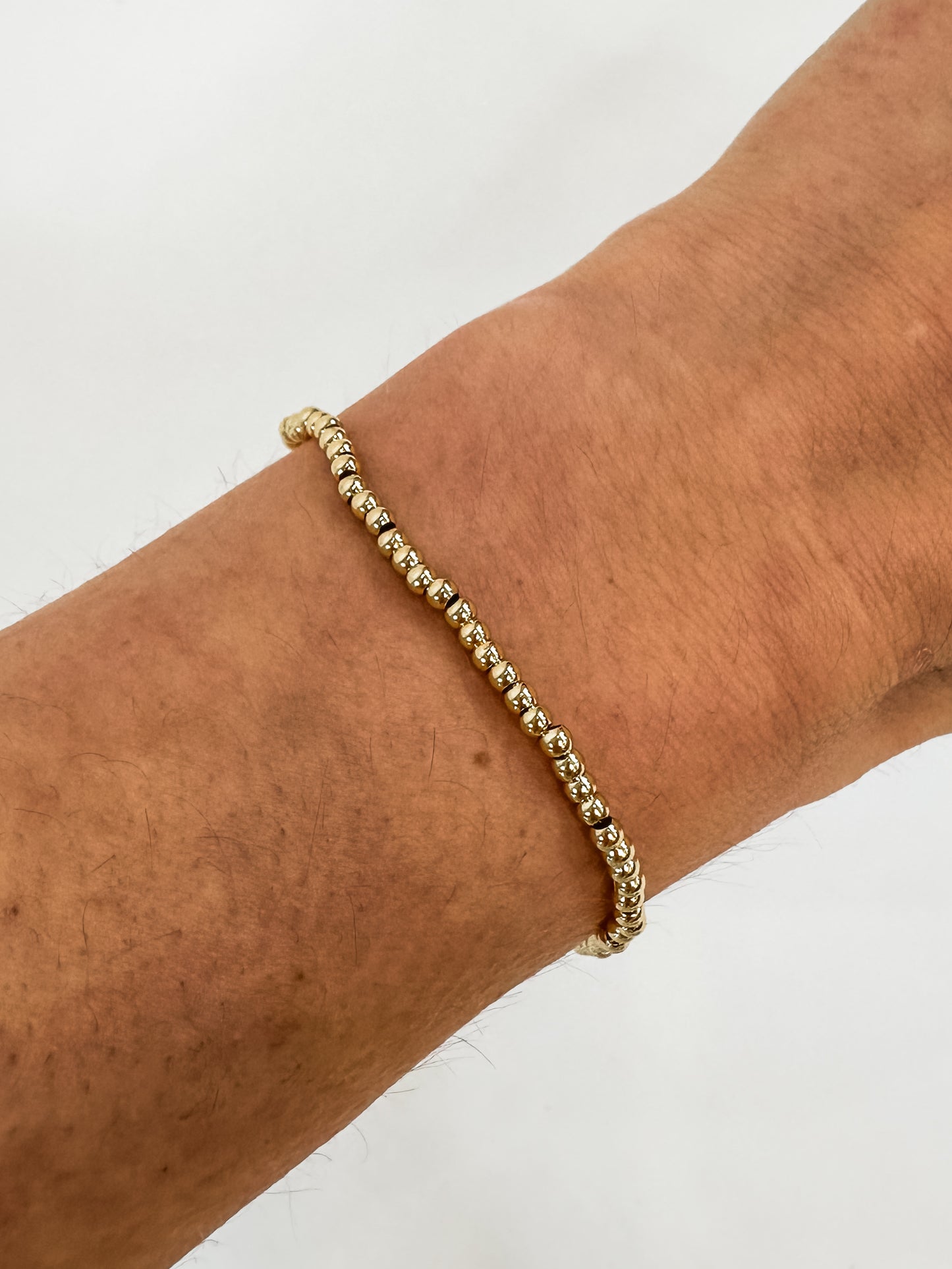 14k gold-filled stacked bracelets on wrist" | "Luxury gold beaded bracelets stacked together