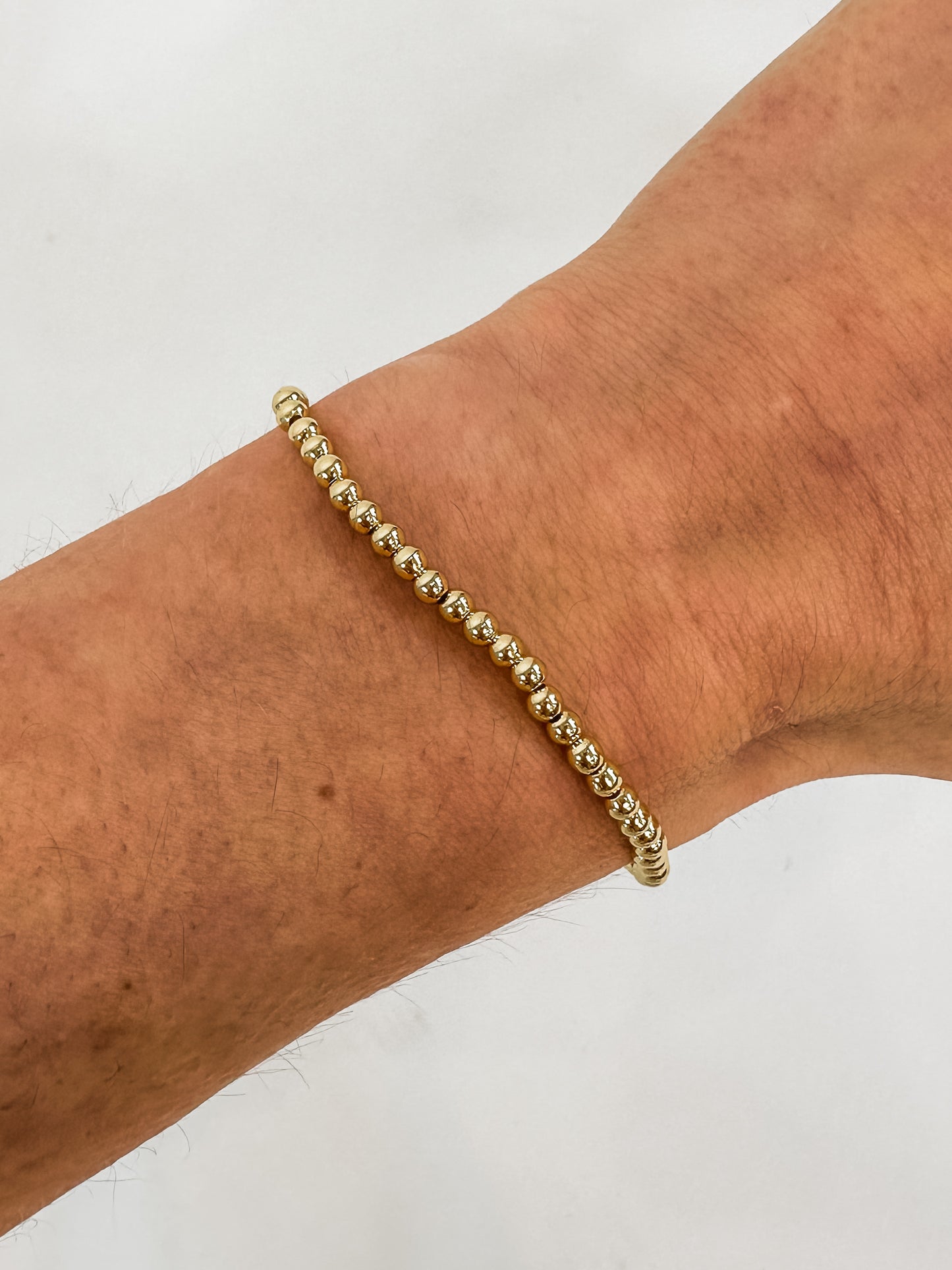 14k gold-filled stacked bracelets on wrist" | "Luxury gold beaded bracelets stacked together