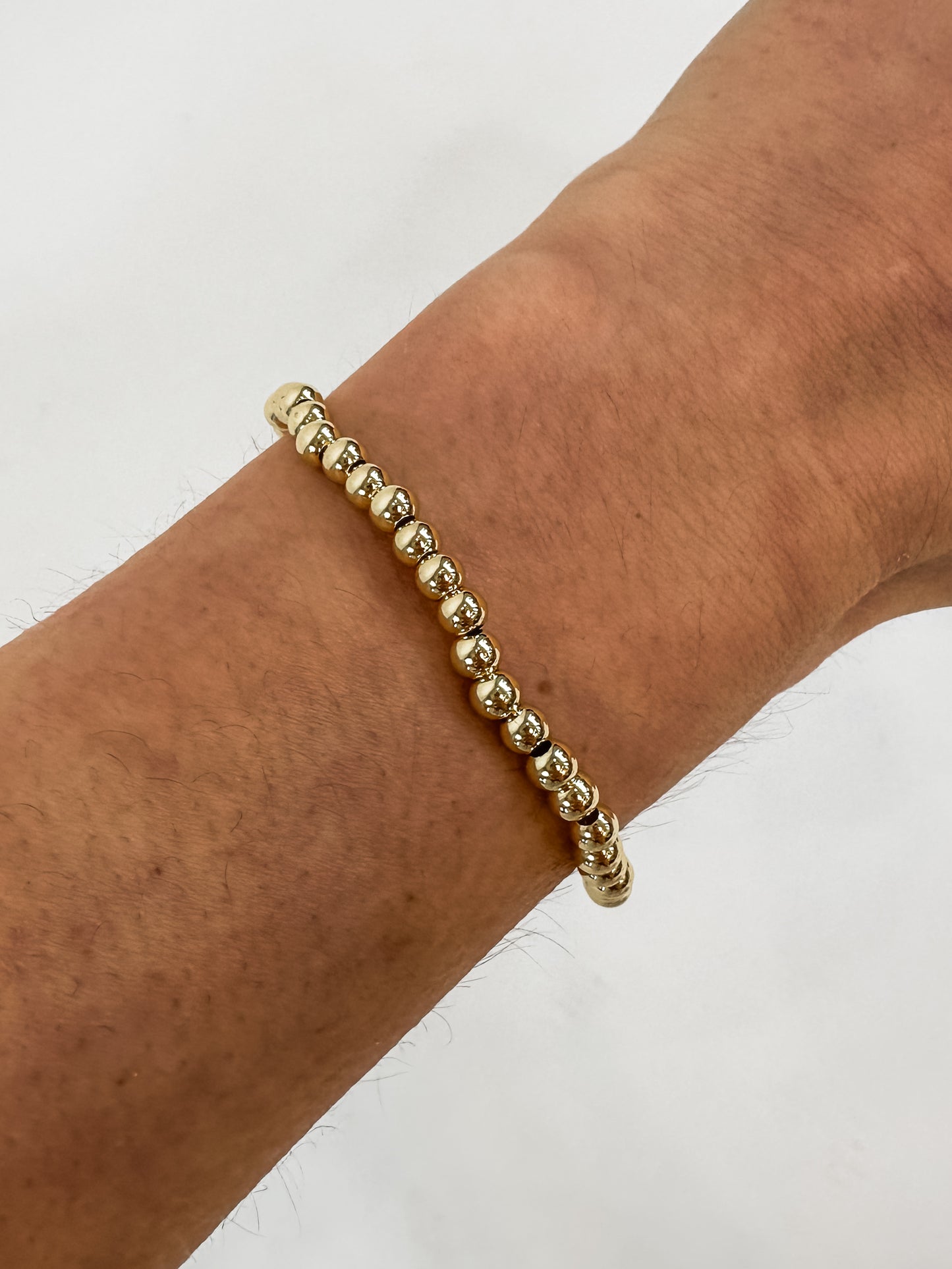 14k gold-filled stacked bracelets on wrist" | "Luxury gold beaded bracelets stacked together