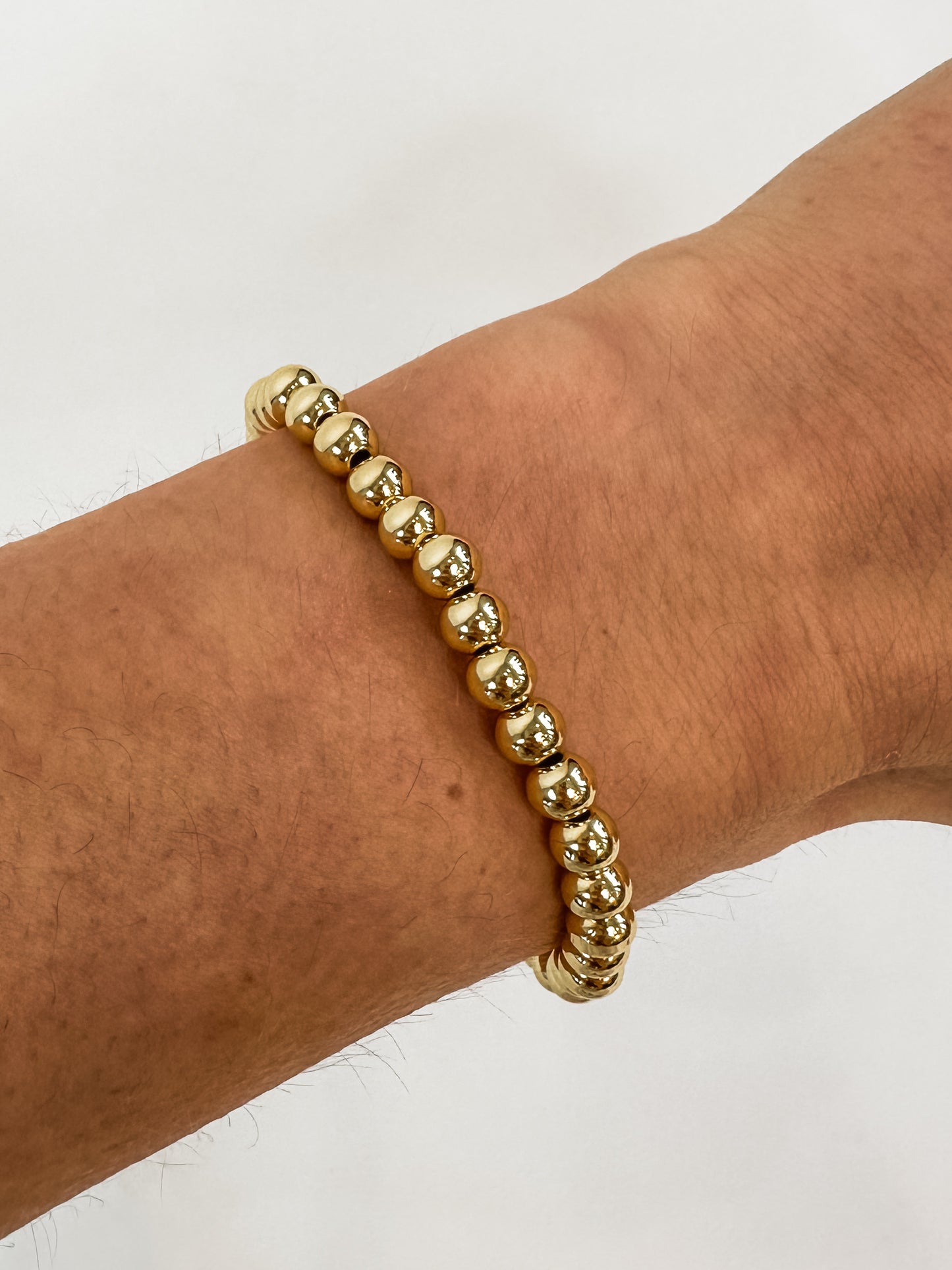 14k gold-filled stacked bracelets on wrist" | "Luxury gold beaded bracelets stacked together