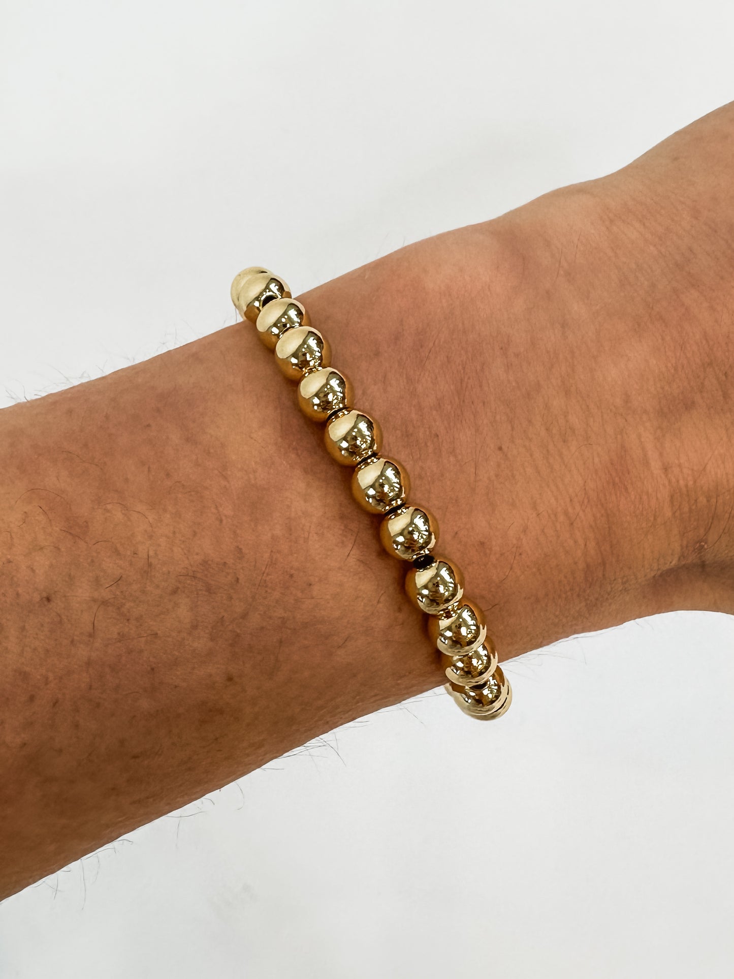 14k gold-filled stacked bracelets on wrist" | "Luxury gold beaded bracelets stacked together