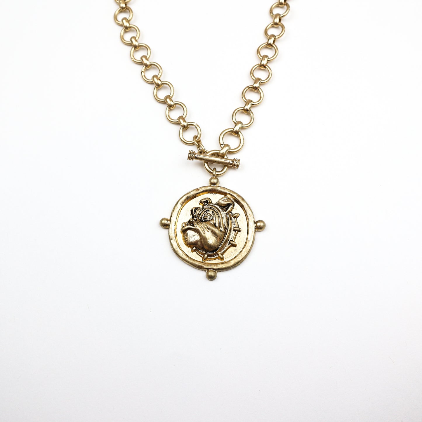 A bold gold-toned medallion necklace featuring an intricately detailed bulldog pendant on a chunky chain with a toggle clasp.