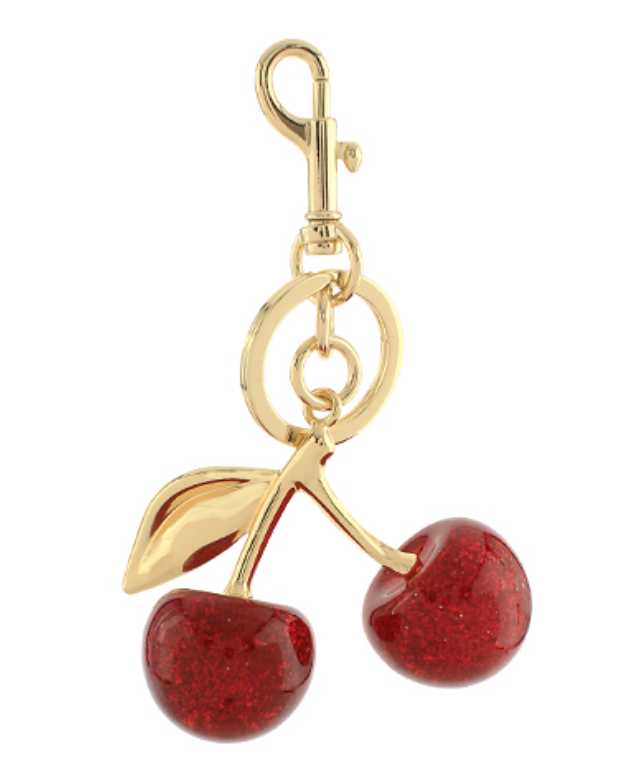 A shiny gold-toned bag charm or keychain featuring a lobster clasp at the top, from which suspends a ring with two bright, glossy red cherry beads, each with a subtle glitter effect, and a gold-toned leaf accent.