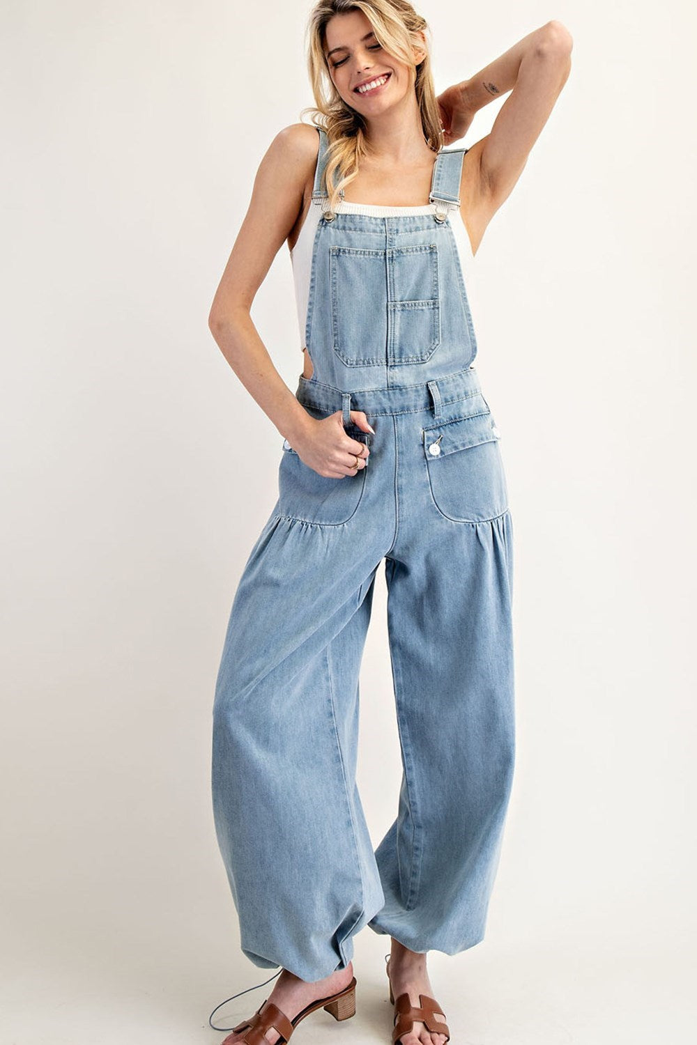 Light-wash denim jumpsuit with a relaxed wide-leg fit, adjustable straps, and a front bib pocket, perfect for casual-chic styling.