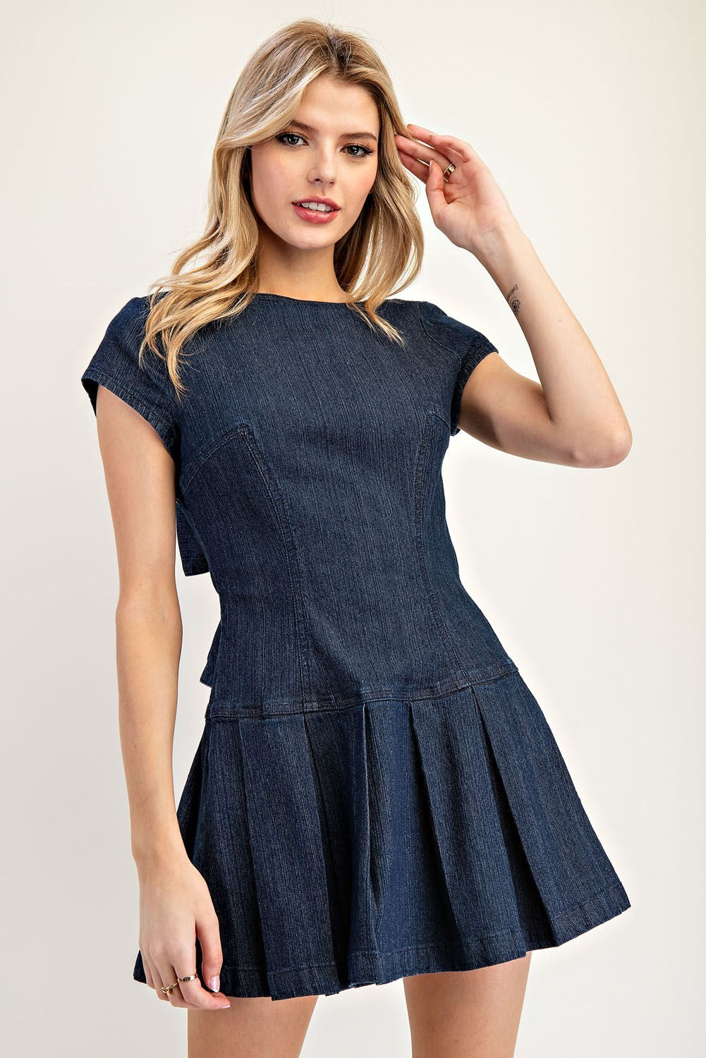 Feminine denim mini dress with pleated skirt and ribbon-tie open back.
