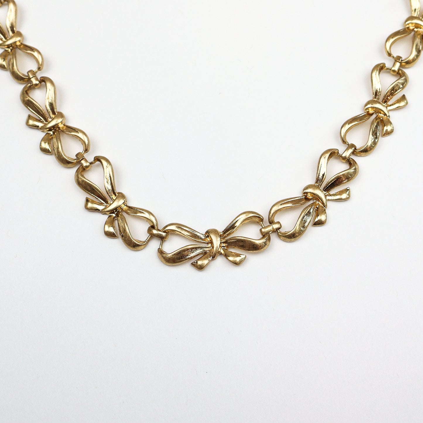 Gold-tone bow chain necklace with intricate link design
