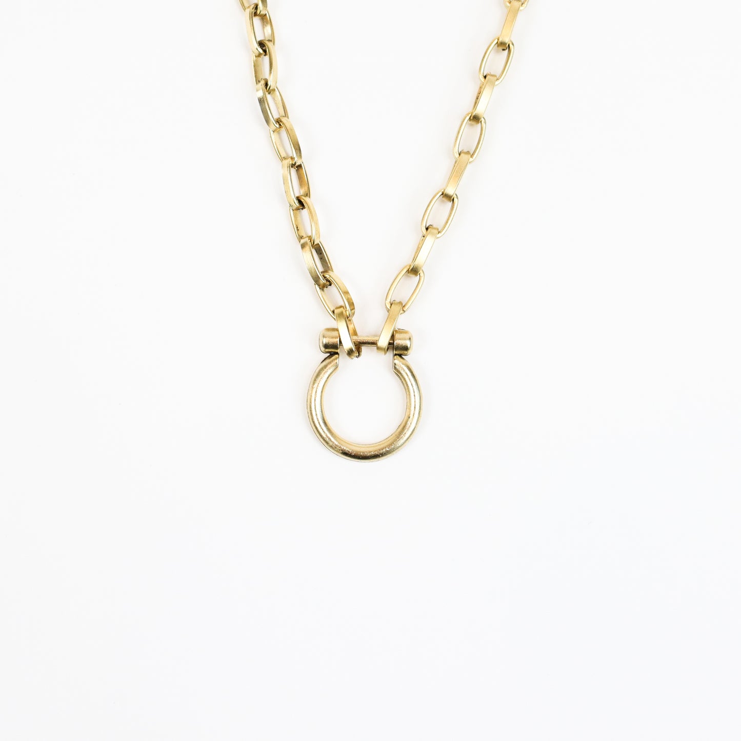 A handcrafted 22K gold-plated necklace featuring a minimalist horse bit pendant suspended on a bold gold chain, blending modern elegance with equestrian charm.