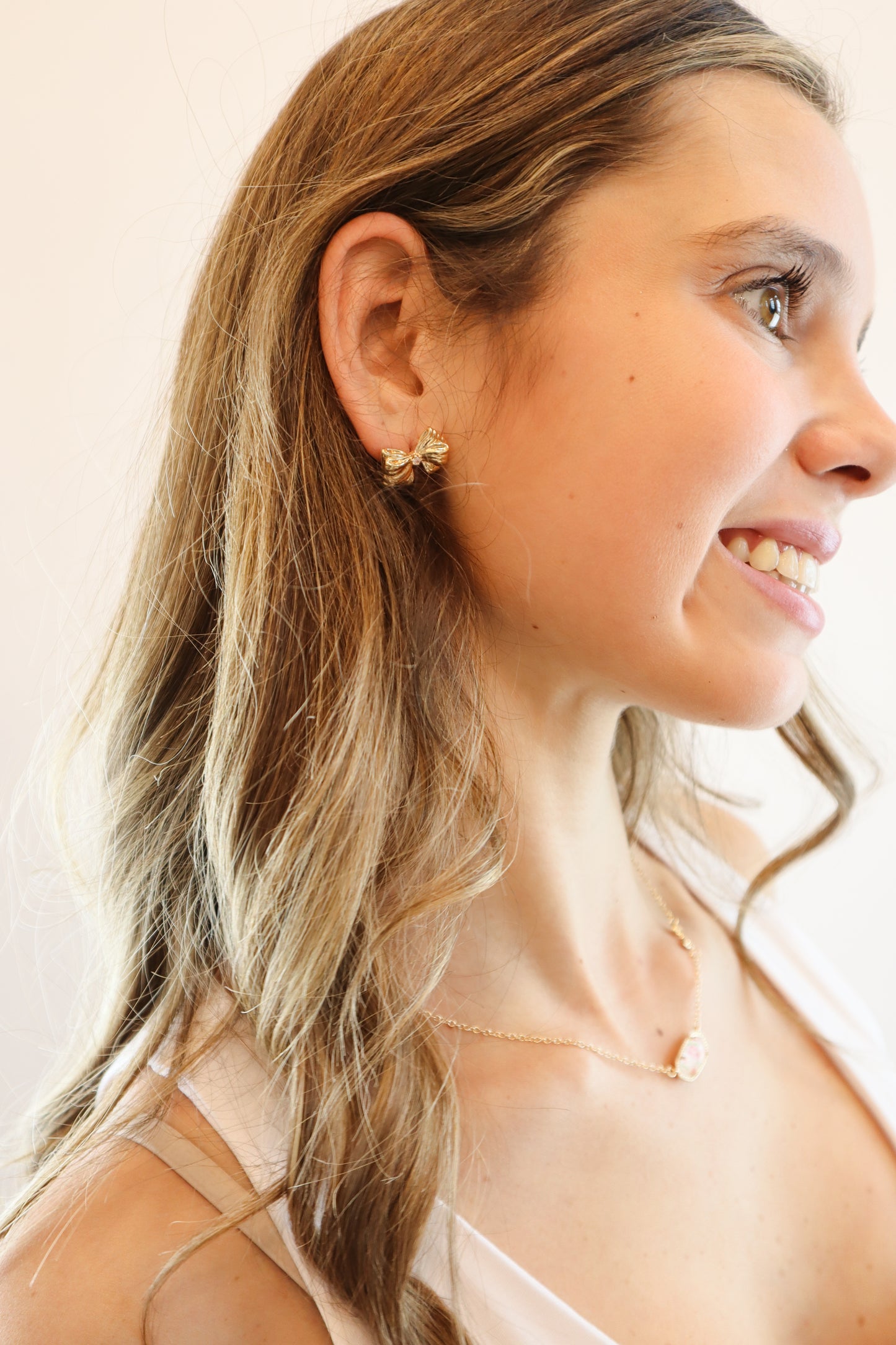 Gold bow stud earrings with a cubic zirconia accent, displayed on a Pieces & Peaches Boutique card—perfect for adding a touch of elegance and femininity to any outfit