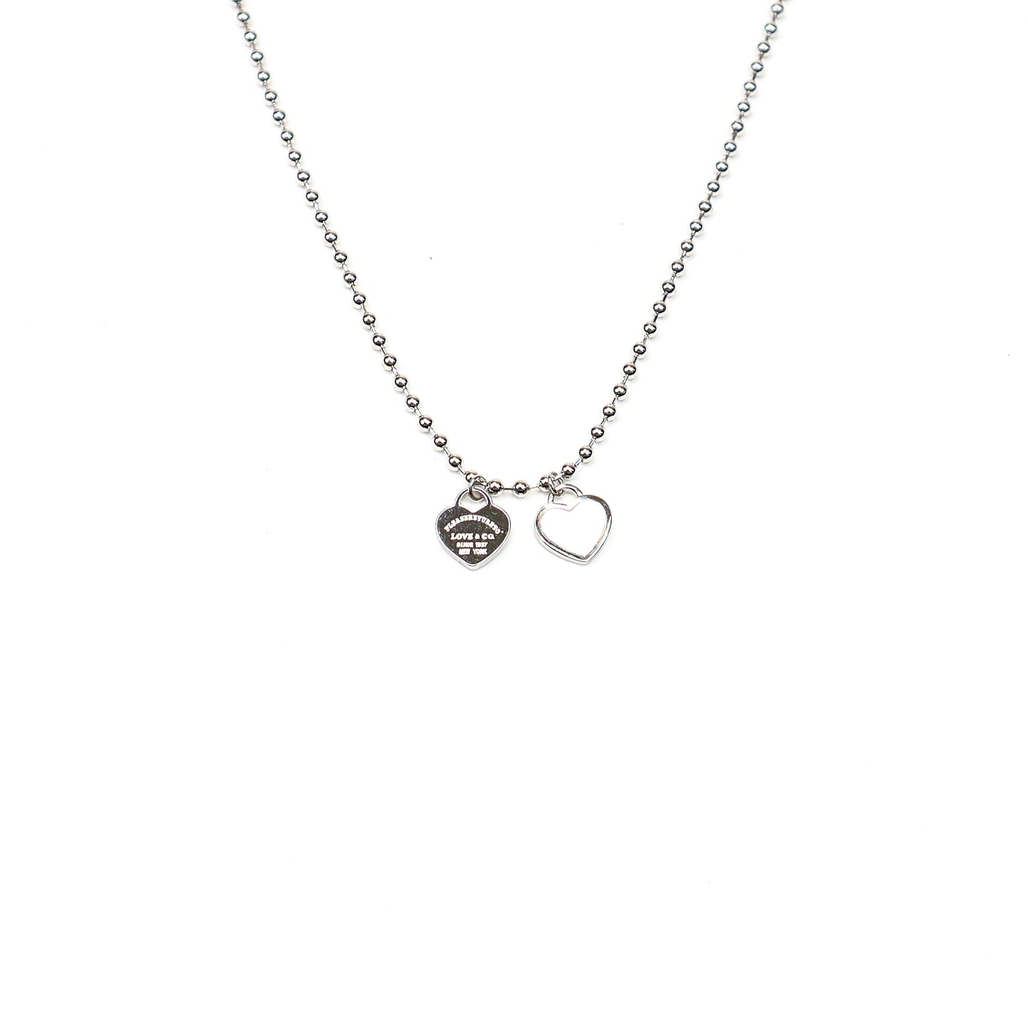 Silver beaded chain necklace with two heart charms, featuring a polished finish and engraved detailing for a timeless, elegant look