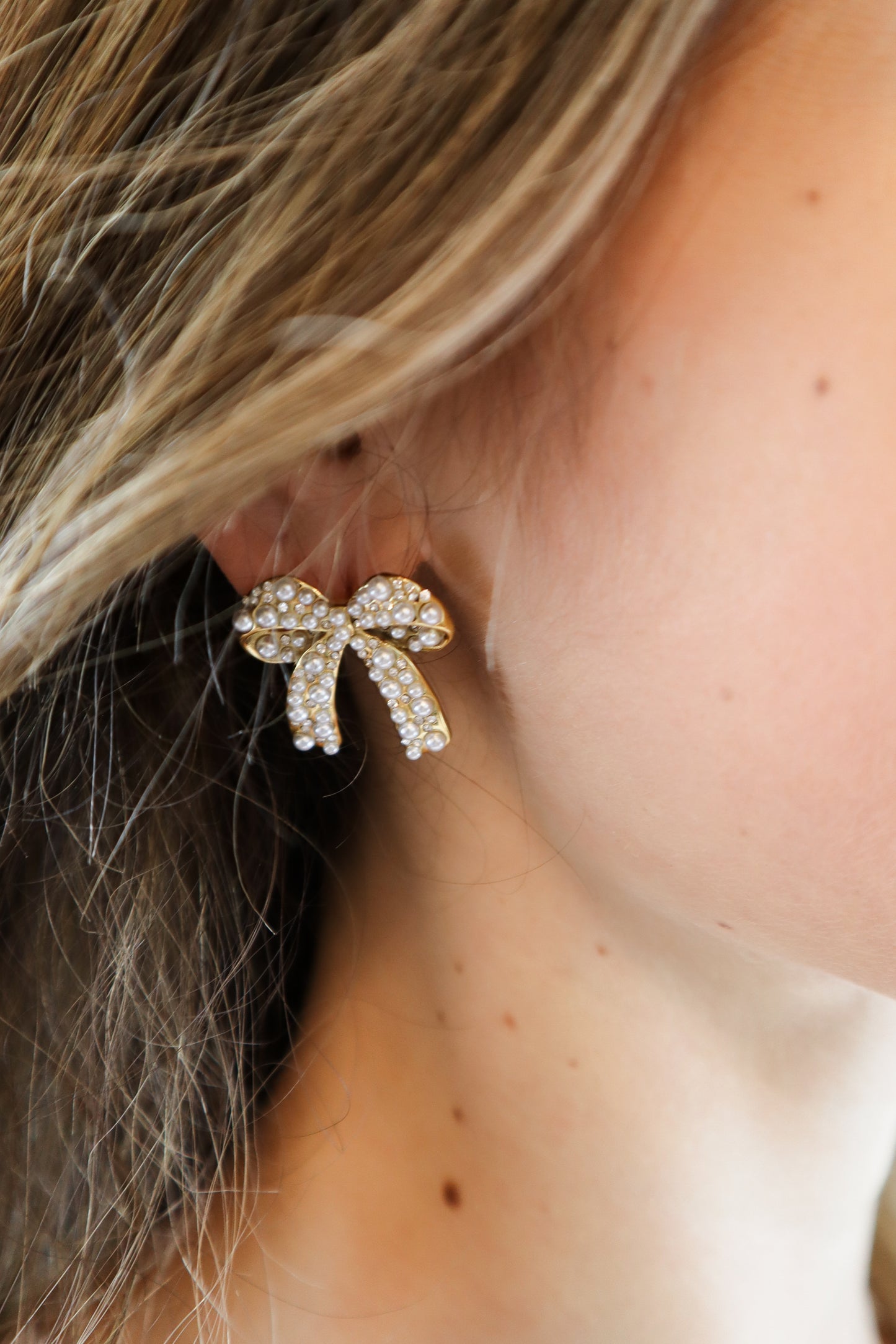 Elegant Pearl Bow Earrings featuring a gold-tone finish, sparkling crystals, and pearl embellishments, perfect for timeless and sophisticated styling.