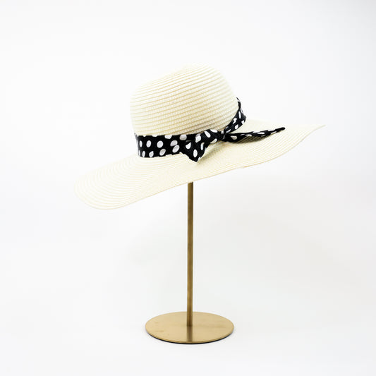 A chic ivory wide-brim sun hat featuring a black polka dot ribbon tied into a stylish bow, perfect for elegant summer outings.