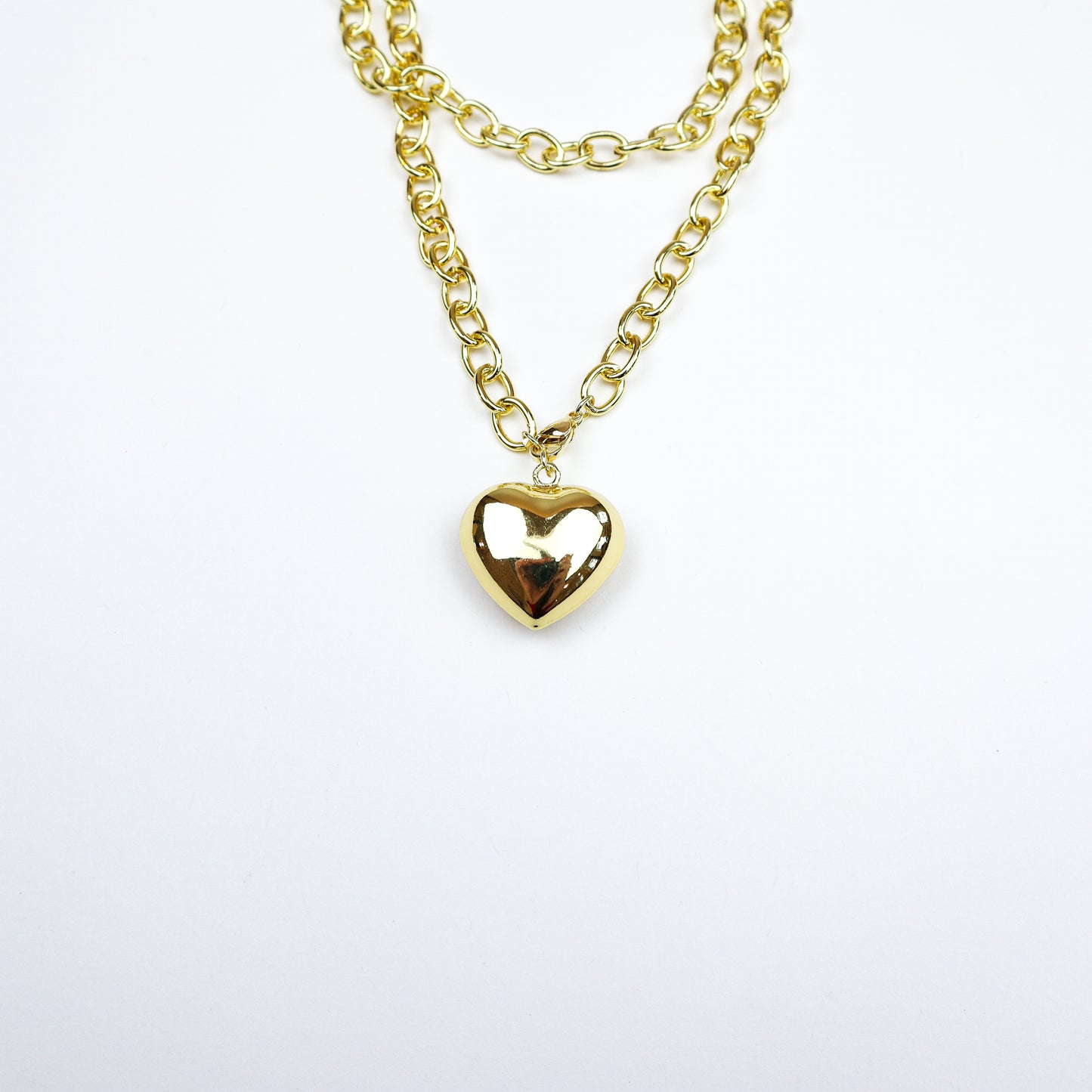 A chic layered gold necklace featuring a bold heart pendant, perfect for adding a touch of romance and elegance to any look.