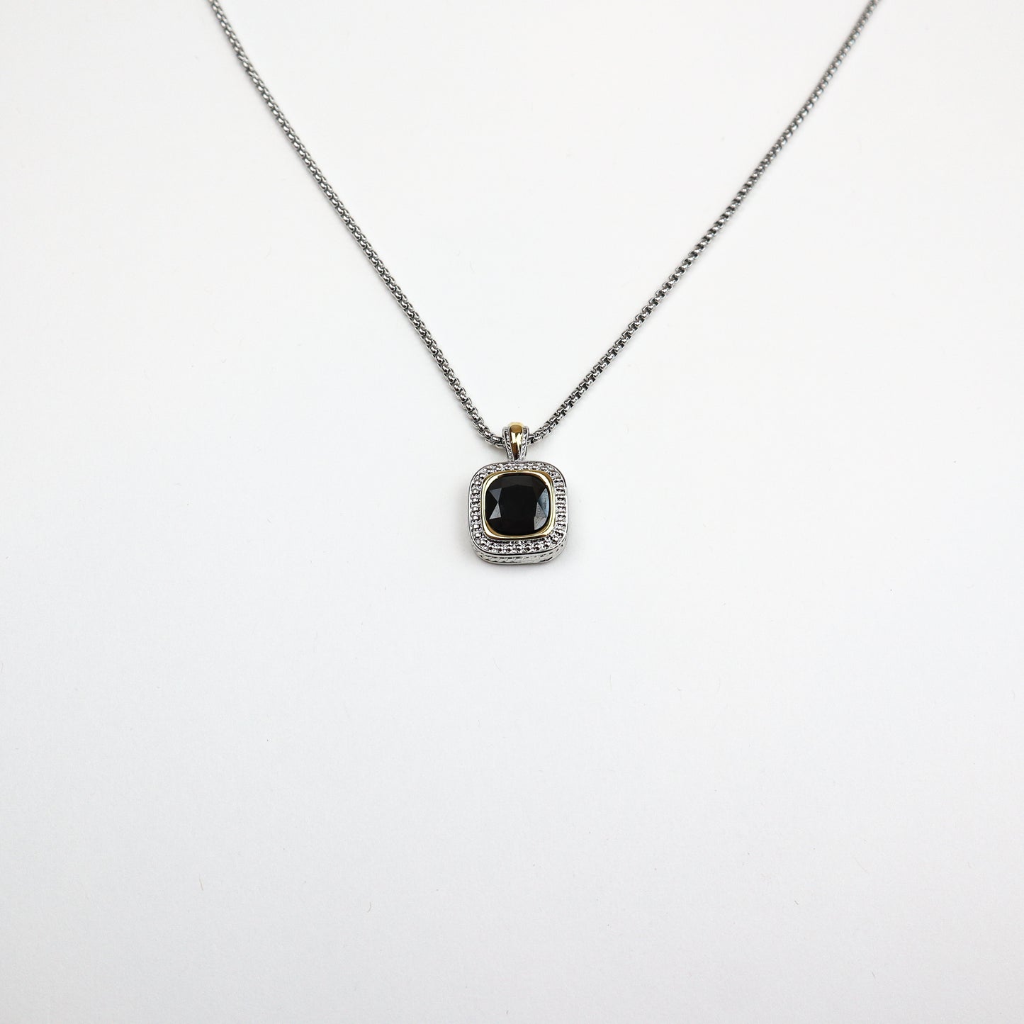 The David Necklace featuring a cushion-cut onyx center, surrounded by shimmering cubic zirconia accents, suspended from a sleek silver-tone chain.