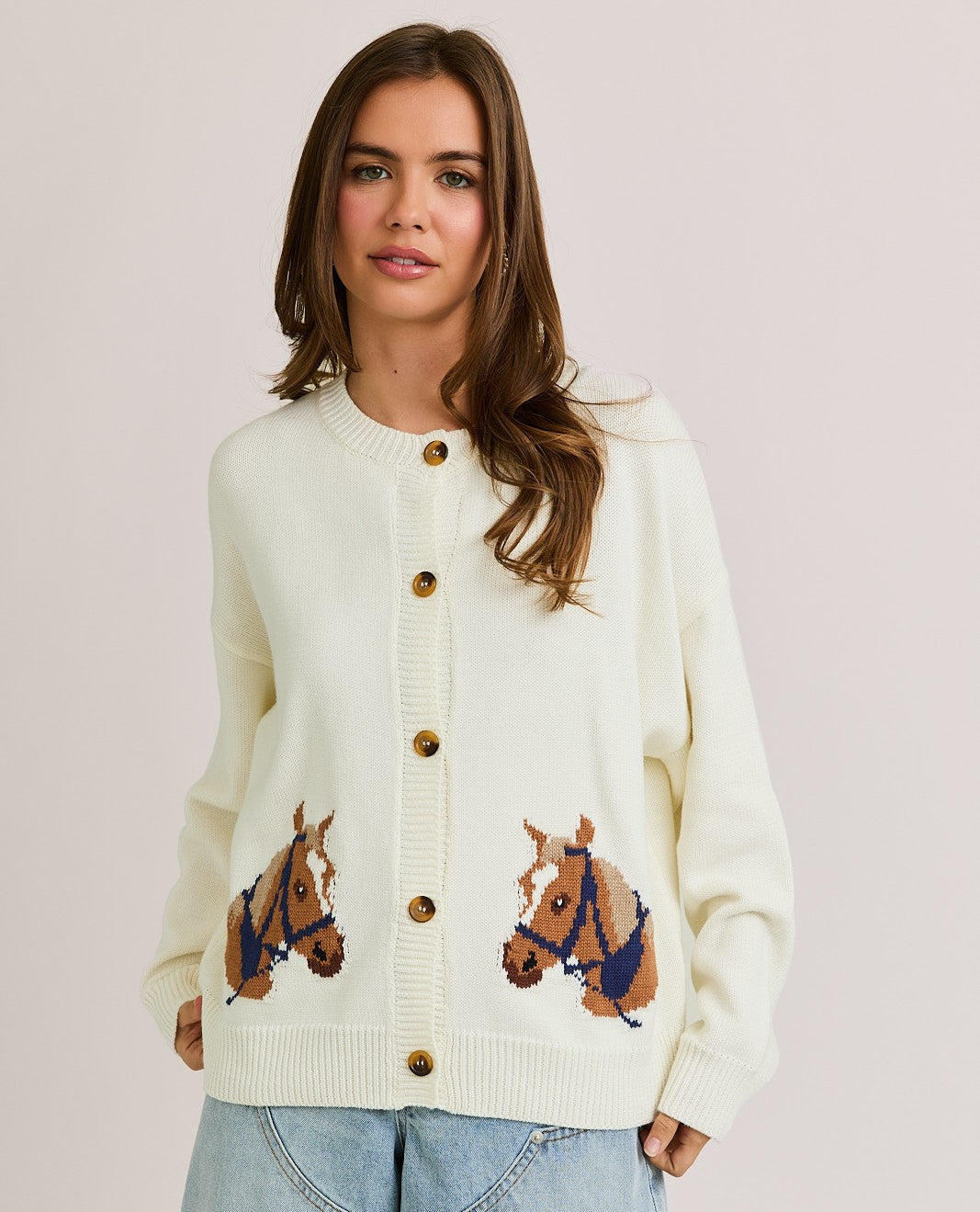 The Bernice Cardigan features a bold horse graphic design with a cozy knit blend, round neckline, and long sleeves for effortless statement layering.
