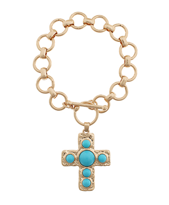 A gold-toned toggle bracelet with large, circular links, featuring a textured gold cross pendant embellished with five round, smooth turquoise cabochon stones.