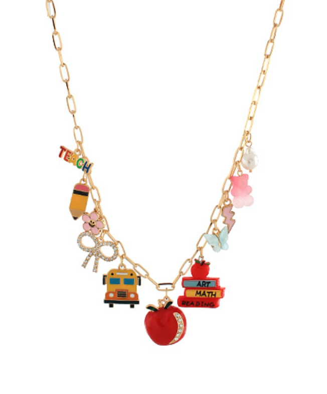 Gold-toned chain necklace featuring an array of colorful enamel charms including the word "TEACH," a pencil, a flower, a glittery bow, a yellow school bus, a red glittery apple, a stack of books labeled "READING," "MATH," and "ART" topped with a red apple, a white flower, a pink teddy bear, a lightning bolt, and a blue butterfly.