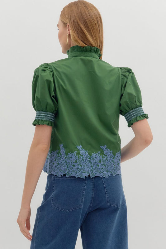 The Greta Embroidered Ruffle Blouse features a romantic ruffle collar, smocked cuffs, and detailed border embroidery for an elevated everyday look.