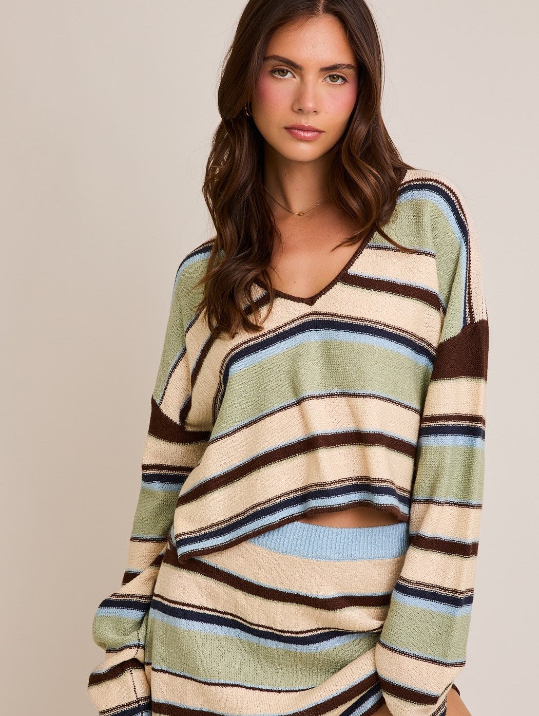 The Ingrid Sweater features bold stripes and a dramatic deep V-neckline in a cropped silhouette—designed for elevated casual layering.