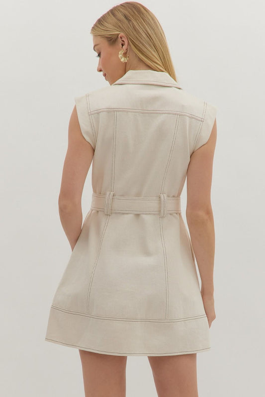 The Rhea Contrast Stitch Mini Dress features sharp tailoring, side pockets, and a self-tie belt for a clean, structured look with subtle edge.