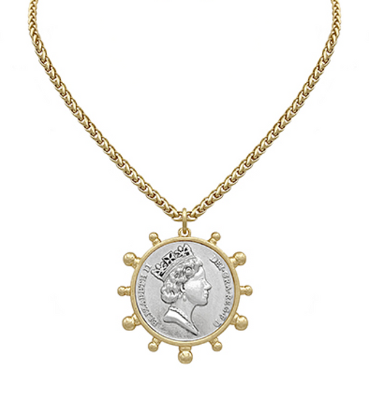 A gold-toned necklace with a substantial chain and a large circular pendant featuring a silver-toned coin insert with a regal profile, possibly Queen Elizabeth II, encircled by gold-toned decorative bumps and rimmed with text.