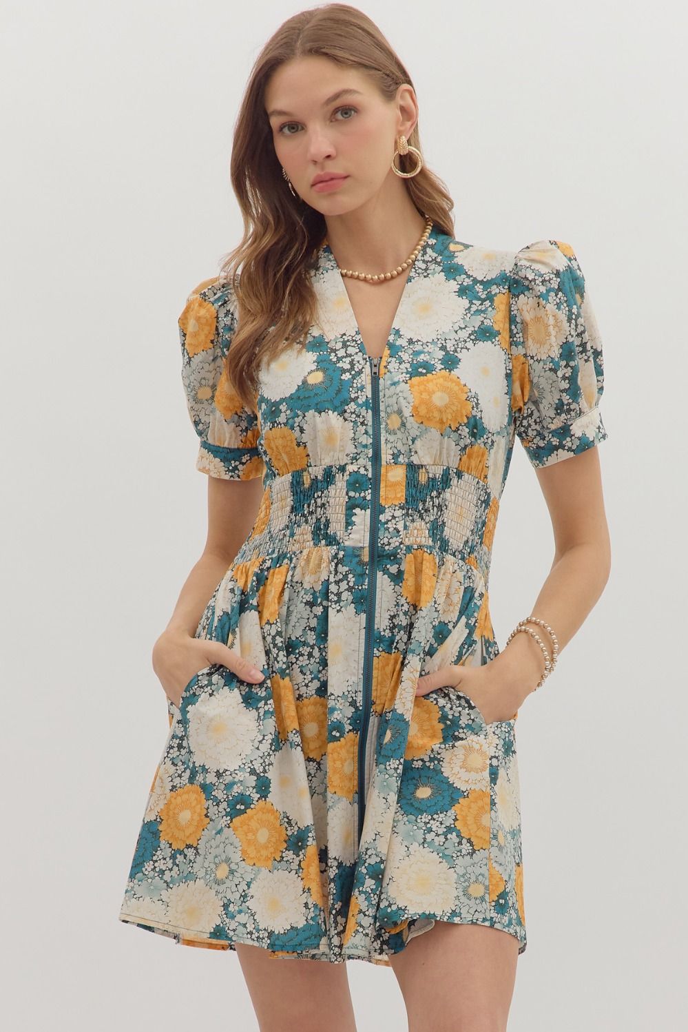 The Veda Floral Smocked Mini Dress features a romantic print, puff sleeves, and a zip-front design for easy, flattering everyday wear.