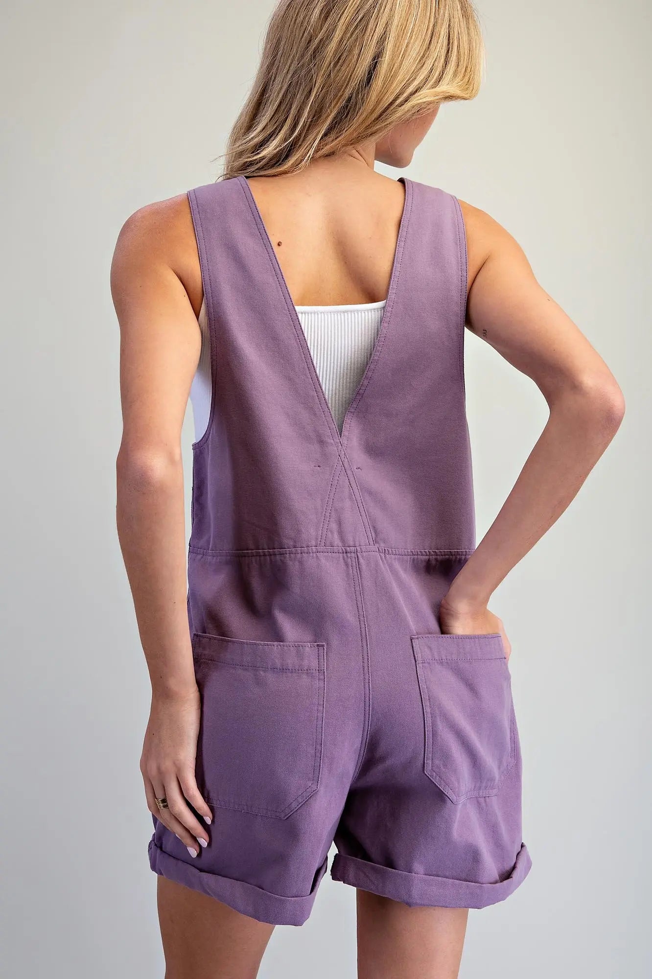 the Elspeth Utility Zip Front Romper featuring a sleeveless utility design, front zipper with snap-button tab, deep V-back, functional pockets, and cuffed hems.