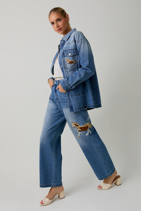 Wide-leg denim pants with embroidered horse motifs and a relaxed, vintage-inspired fit.