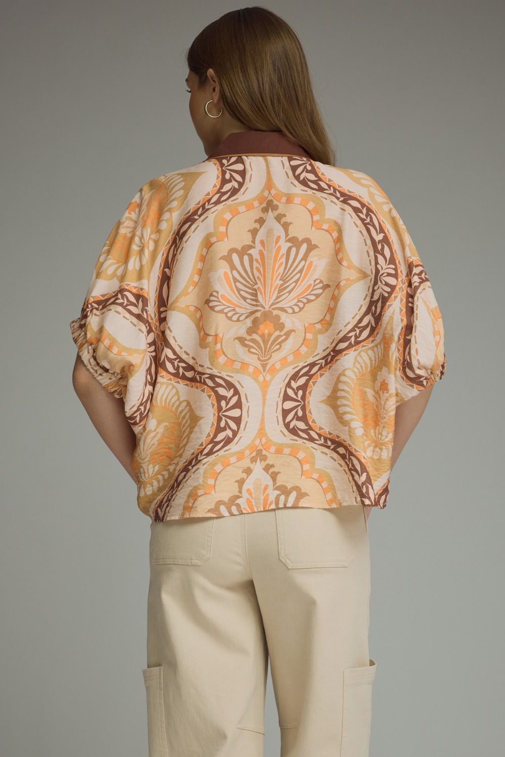 A lightweight abstract print blouse featuring relaxed dolman sleeves, contrast trim details, and an effortlessly chic silhouette.