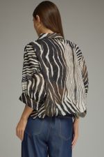 A chic zebra-print woven top featuring dramatic poncho sleeves, a classic shirt collar, button-front closure, and a feminine scalloped hem.