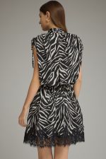 A statement-making zebra print mini dress featuring a mock neckline, self-tie shoulder details, elastic waist, and delicate lace-trimmed hem.