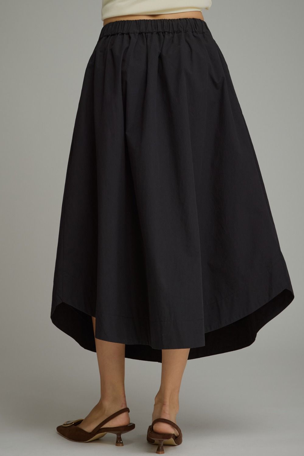 A timeless midi skirt featuring a button-front design, comfortable elastic waistband, and functional side pockets for effortless everyday elegance.