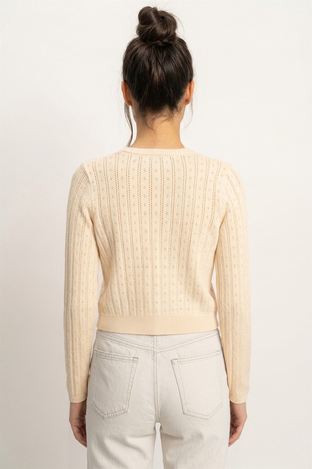 A timeless pointelle knit cardigan featuring a classic button-front design, ribbed crew neckline, and a tailored silhouette for effortless everyday elegance.