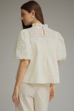 A feminine short sleeve top featuring a romantic ruffled neckline, delicate eyelet detailing, and crochet trim for a beautifully textured boutique look.