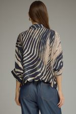 A bold and stylish zebra-print blouse featuring flowing poncho sleeves, a classic shirt collar, button-front closure, and a feminine scalloped hem.