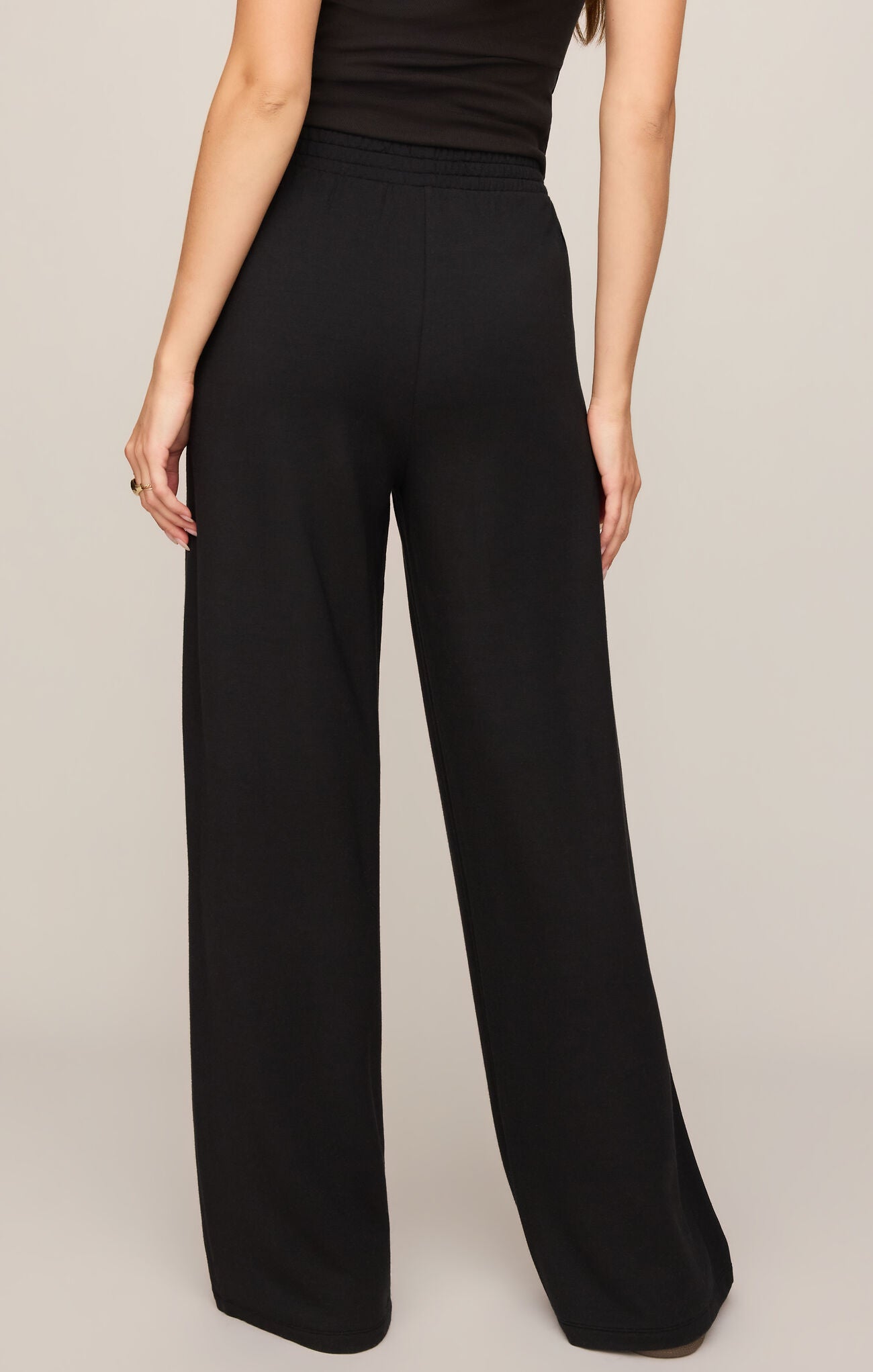 Black wide-leg pants worn by a person on a beige background