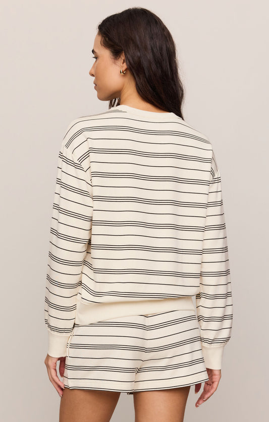 Woman wearing a striped long-sleeve top and shorts on a plain background