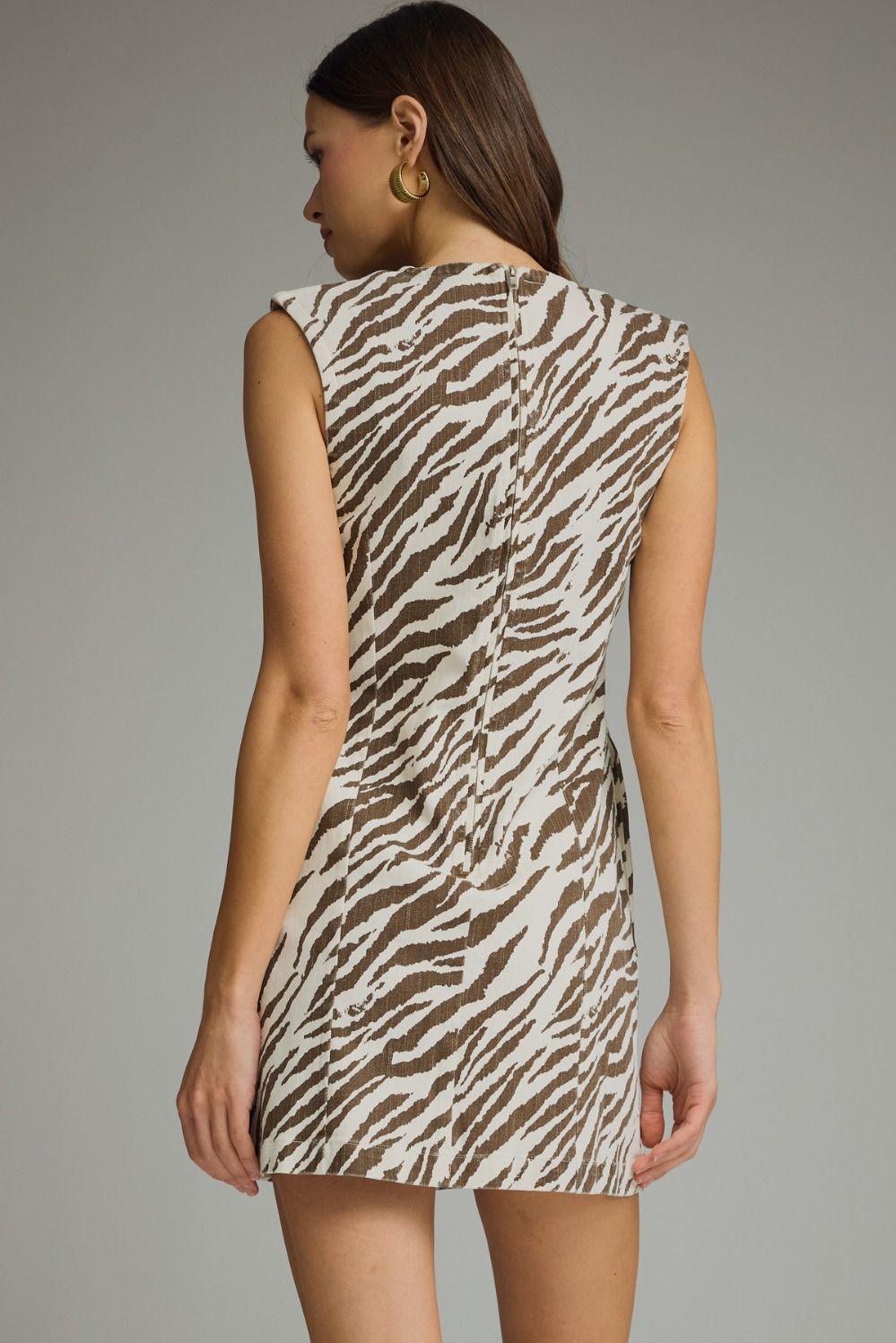 A bold zebra print mini dress featuring eye-catching shoulder detail, a sleek sleeveless silhouette, and convenient side pockets.