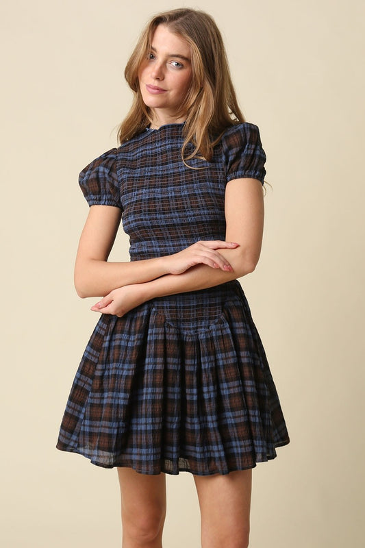 A timeless plaid mini dress featuring a flattering smocked bodice, feminine cap sleeves, and a softly gathered fit-and-flare skirt in breathable cotton.